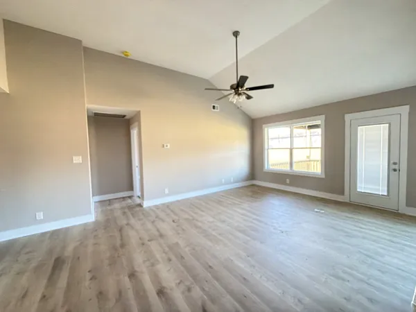 a view of empty room with wooden floor and fan