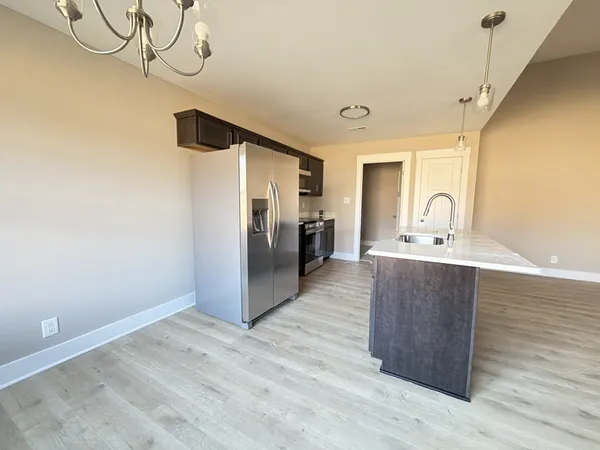 a kitchen with kitchen island a counter top space wooden floor and a refrigerator