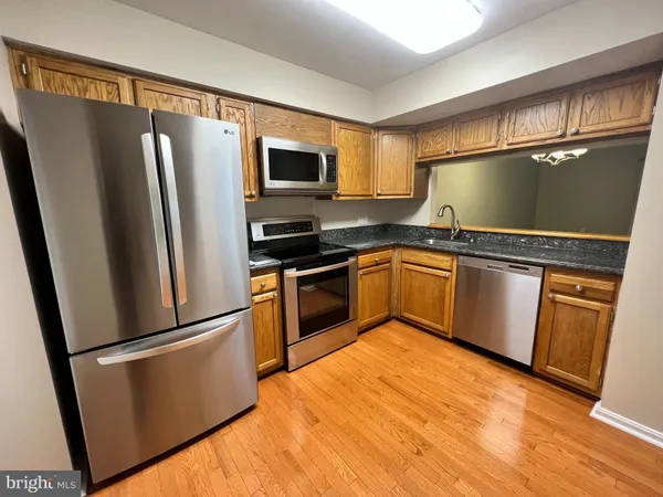 a kitchen with granite countertop stainless steel appliances a refrigerator a sink and cabinets