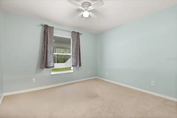 an empty room with a window and a ceiling fan