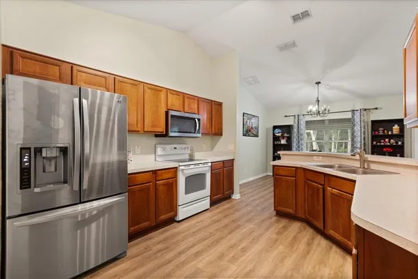 a large kitchen with stainless steel appliances granite countertop a refrigerator a stove top oven a sink dishwasher and wooden cabinets with wooden floor