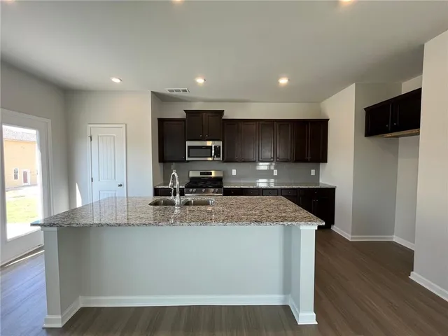 a large kitchen with stainless steel appliances granite countertop a sink a stove a microwave a refrigerator and cabinets