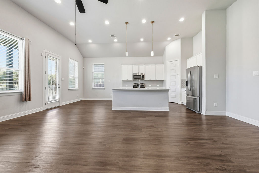 2032 Base Burner Path Leander, TX 78641 - Photo 6 of 34 Open-concept living space featuring wood-finish flooring, vaulted ceilings, and recessed lighting