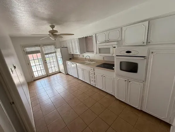 a kitchen with granite countertop white cabinets and white appliances