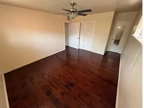 an empty room with wooden floor and fan