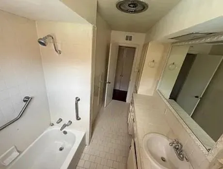 a bathroom with a tub a sink and a large mirror