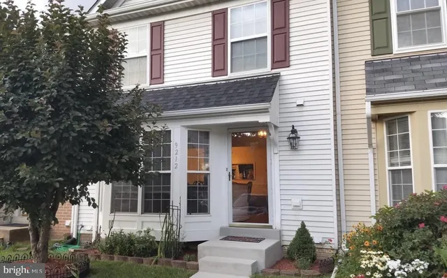 a view of a brick house with a large windows and plants and trees