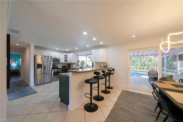 a kitchen with stainless steel appliances kitchen island granite countertop a refrigerator a stove a sink a dining table and chairs with wooden floor