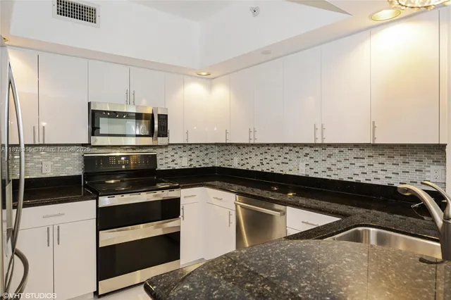 a kitchen with granite countertop white cabinets and stainless steel appliances