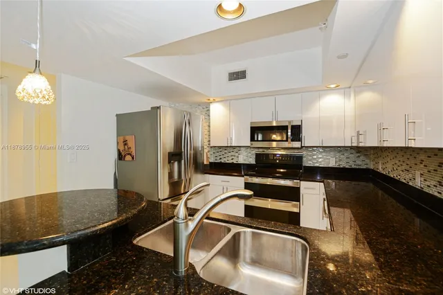 a kitchen with granite countertop a sink stainless steel appliances and cabinets