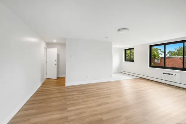 a view of an empty room with window and wooden floor