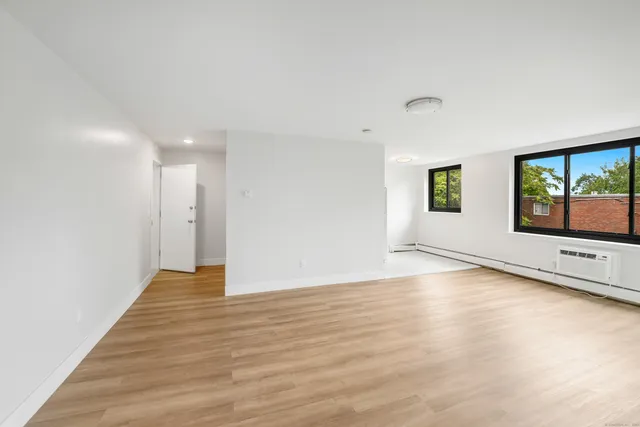 a view of an empty room with window and wooden floor