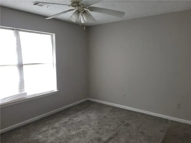 an empty room with a window and a fan
