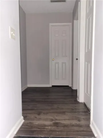 a view of an empty room with wooden floor and closet
