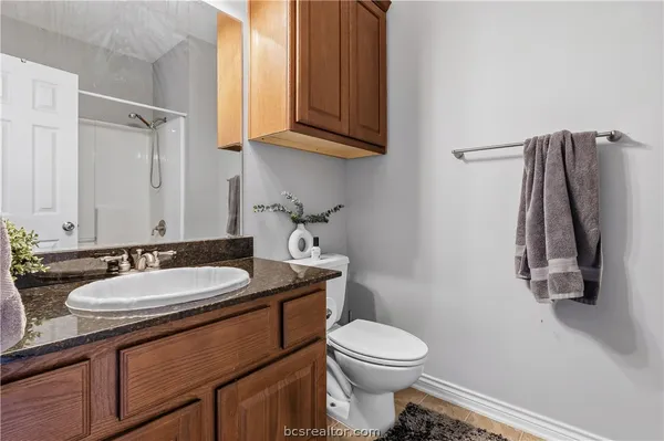 a bathroom with a granite countertop toilet sink and mirror