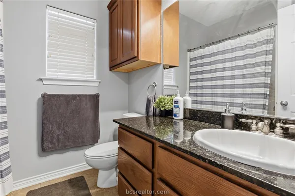 a bathroom with a granite countertop sink a toilet and mirror