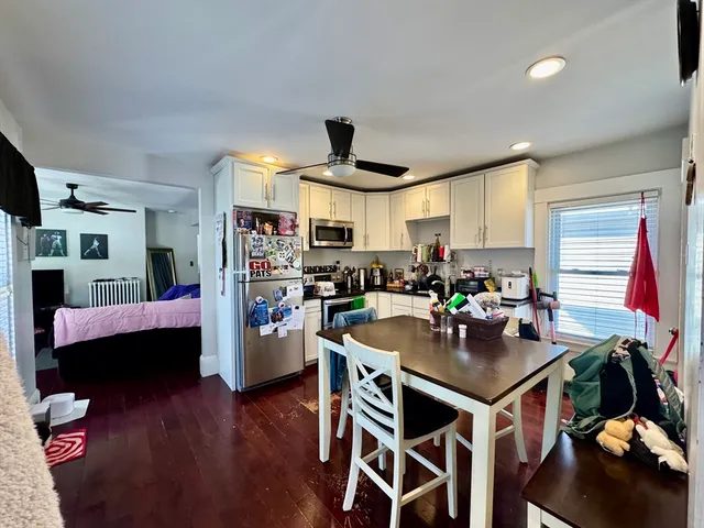 a kitchen with stainless steel appliances kitchen island granite countertop a table chairs and a refrigerator