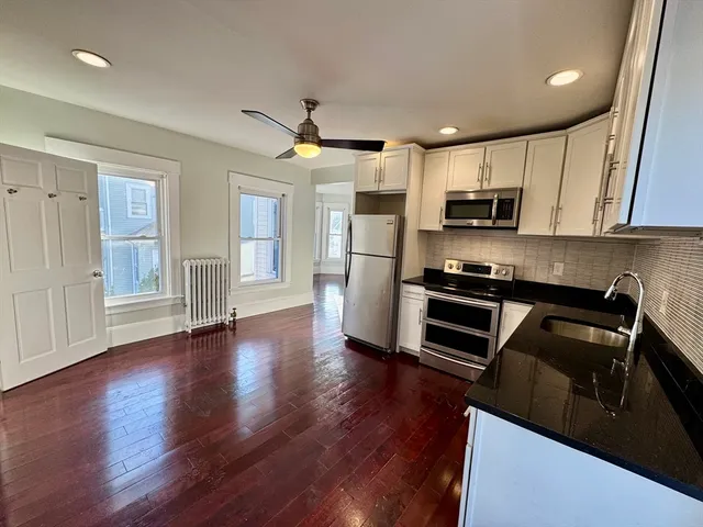 a kitchen with kitchen island wooden floors appliances and cabinets