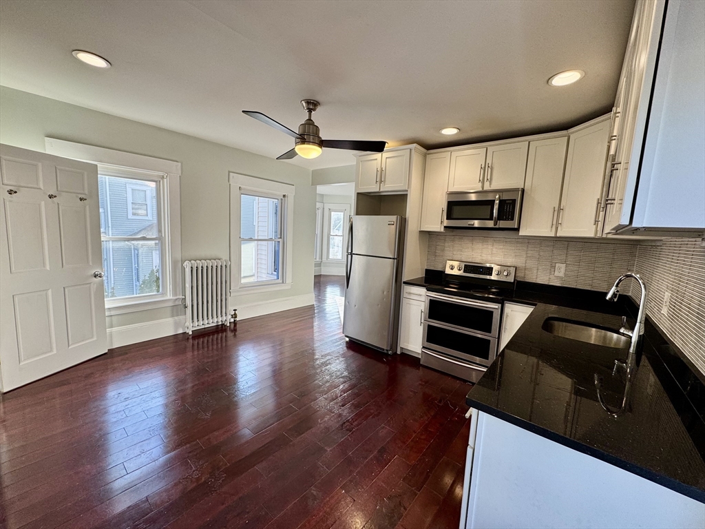 6 Gould Street, Unit 2 Stoneham, MA 02180 - Photo 6 of 27 a kitchen with kitchen island wooden floors appliances and cabinets