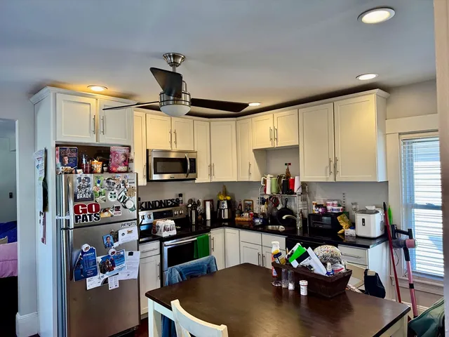 a kitchen with a refrigerator a stove a sink a dining table and chairs with wooden floor