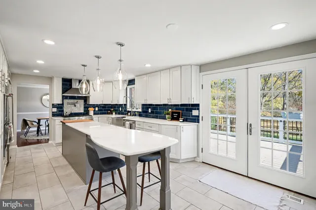 a kitchen with stainless steel appliances granite countertop a refrigerator a sink dishwasher a stove and white cabinets with wooden floor