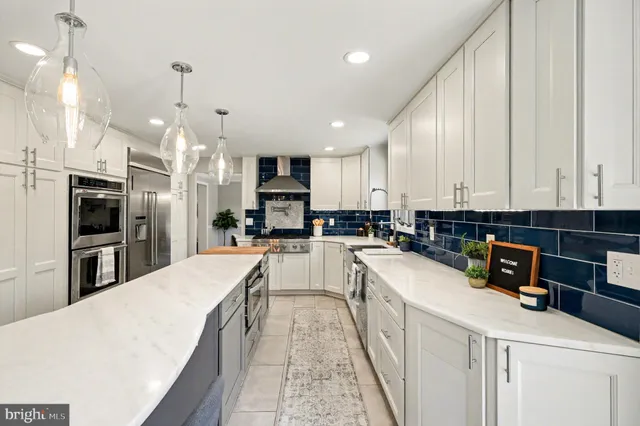 a kitchen with stainless steel appliances a sink a stove a refrigerator cabinets and a window