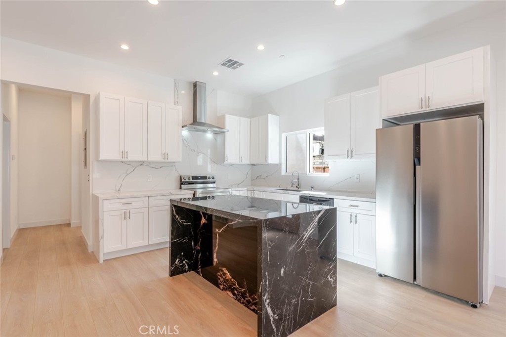 6852 Ranchito Avenue Van Nuys, CA 91405 - Photo 6 of 18 a kitchen with a sink a stove a refrigerator and white cabinets