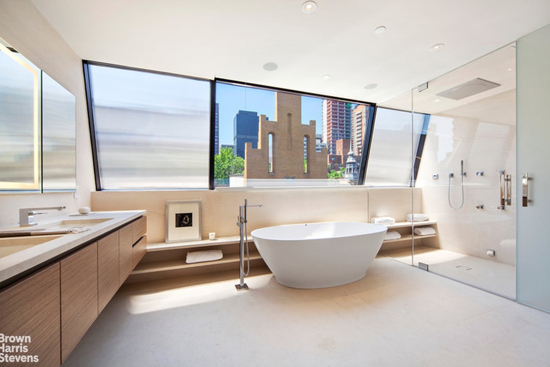 251 East 61st Street Manhattan, NY 10065 - Photo 15 of 39 a spacious bathroom with a large tub a sink and a large mirror next to a window