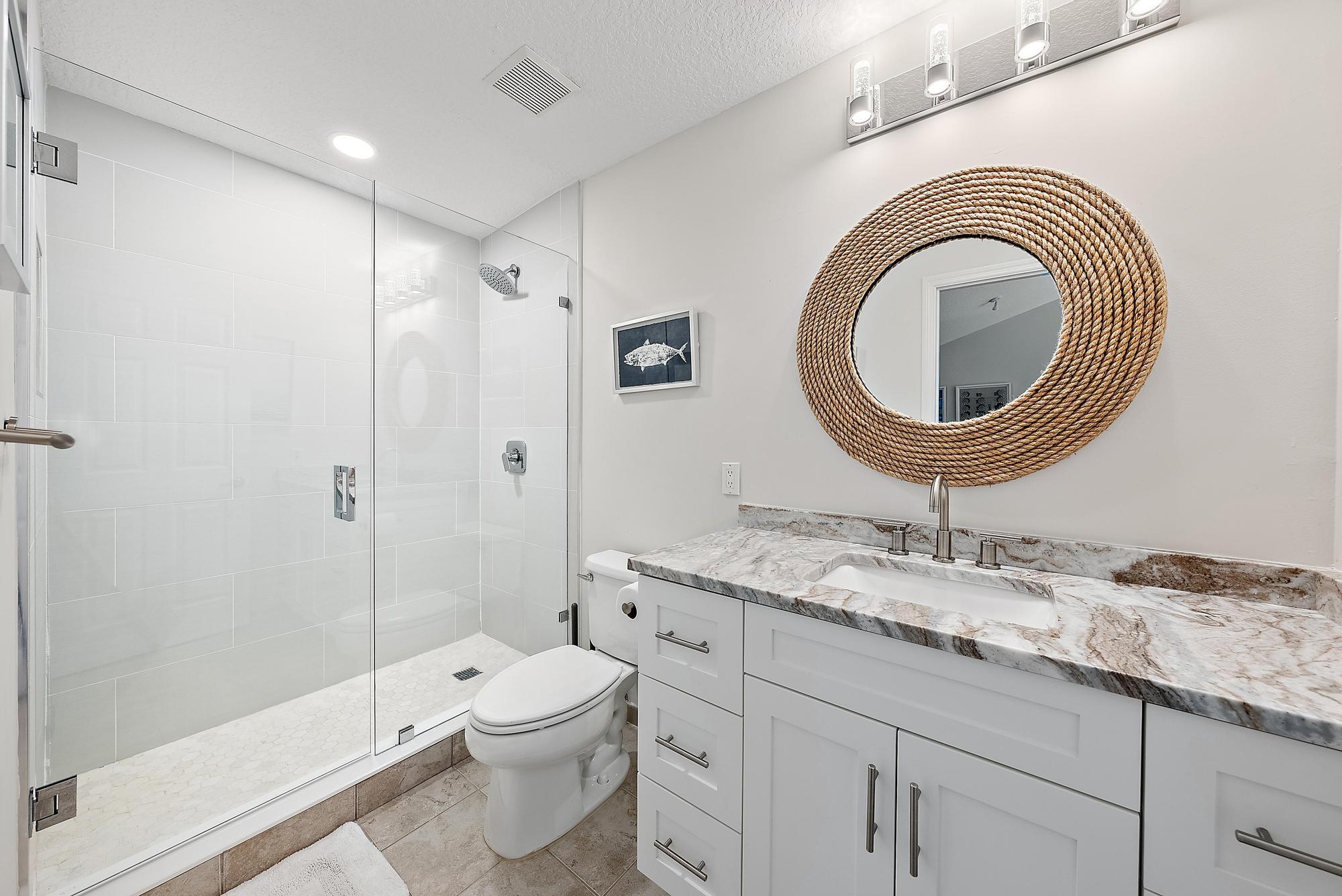 1000 North Us Highway, Unit 700 Jupiter, FL 33477 - Photo 23 of 32 a bathroom with a granite countertop toilet a sink and a mirror