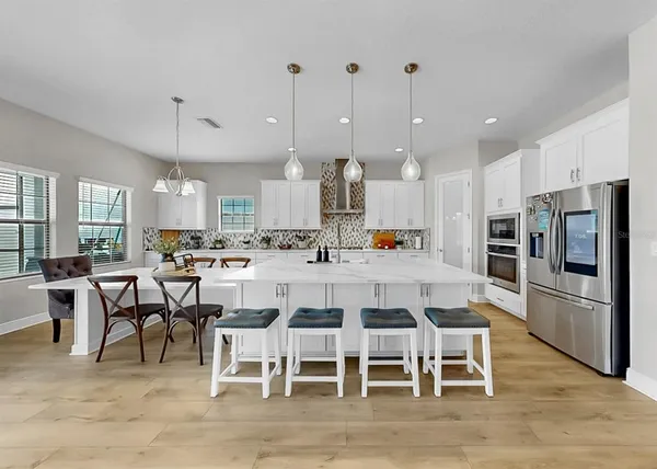 a kitchen with stainless steel appliances granite countertop a sink a stove a dining table and chairs