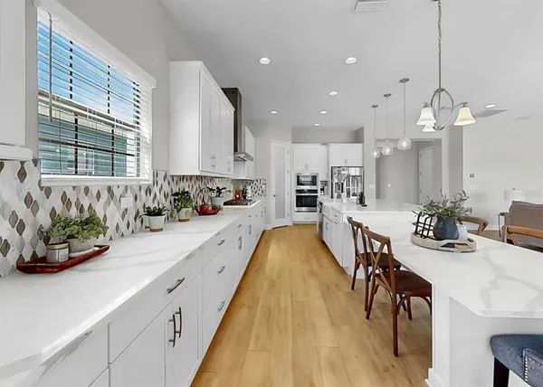 a large kitchen with a sink a counter space stainless steel appliances and cabinets