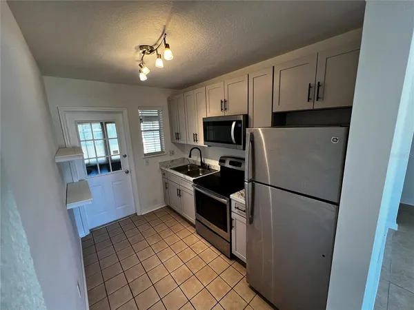 a kitchen with a refrigerator a stove top oven and cabinets