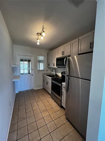 a kitchen with a refrigerator a stove top oven and cabinets