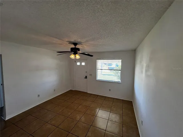 an empty room with windows and fan