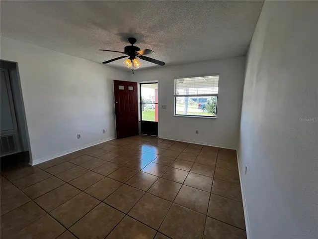 an empty room with windows and fan