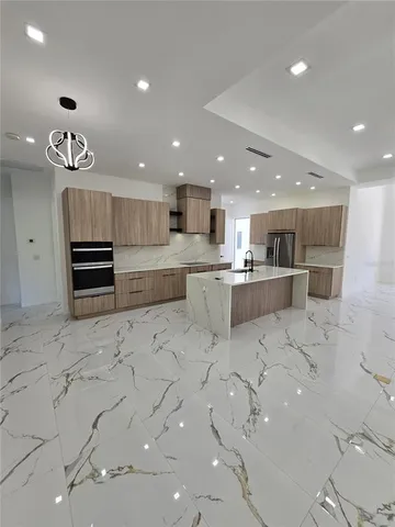a large kitchen with stainless steel appliances lots of white cabinets