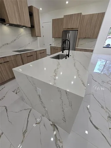 a kitchen with stainless steel appliances a sink a refrigerator and cabinets