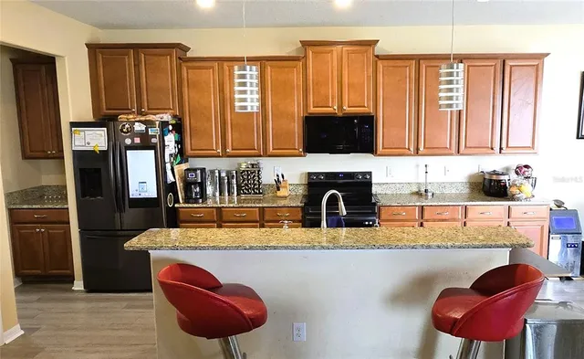 a kitchen with stainless steel appliances granite countertop a sink dishwasher and a refrigerator with wooden floor