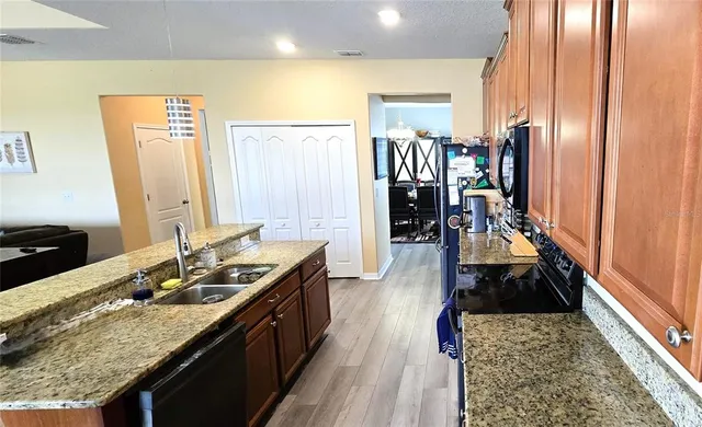 a kitchen with granite countertop a sink stove and cabinets