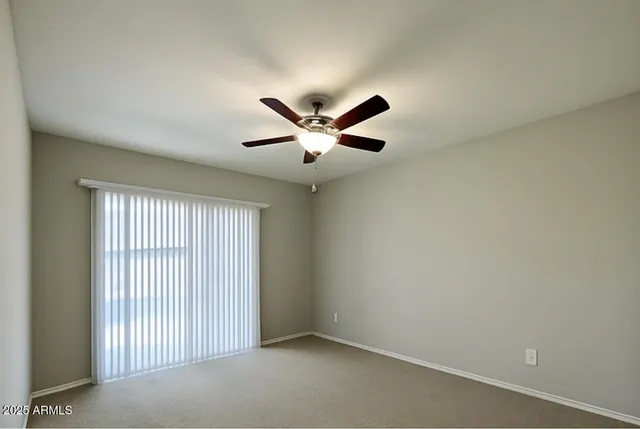 an empty room with ceiling fan and windows