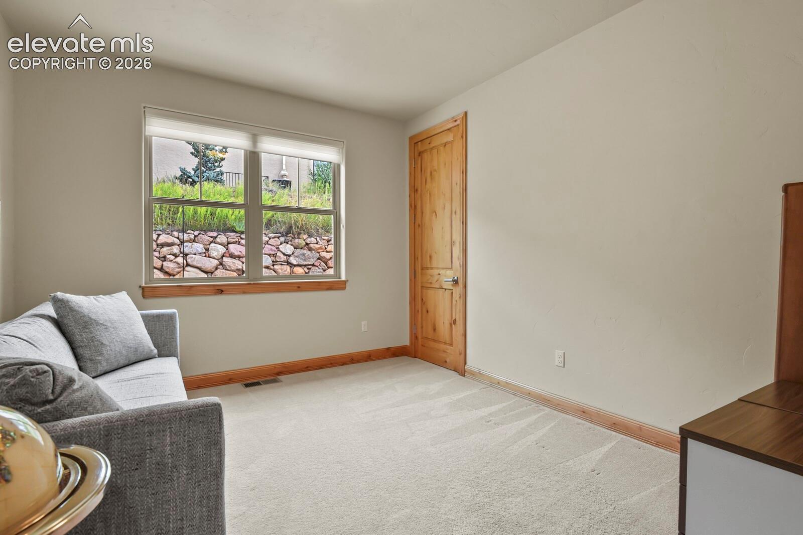 5545 Wilson Road Colorado Springs, CO 80919 - Photo 23 of 48 Main level bedroom with a large window, natural wood trim, and a wood-paneled door, walk-in closet
