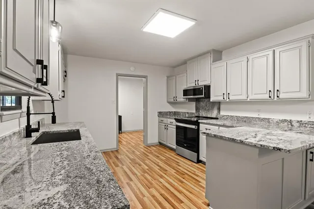 a kitchen with granite countertop a stove sink and microwave