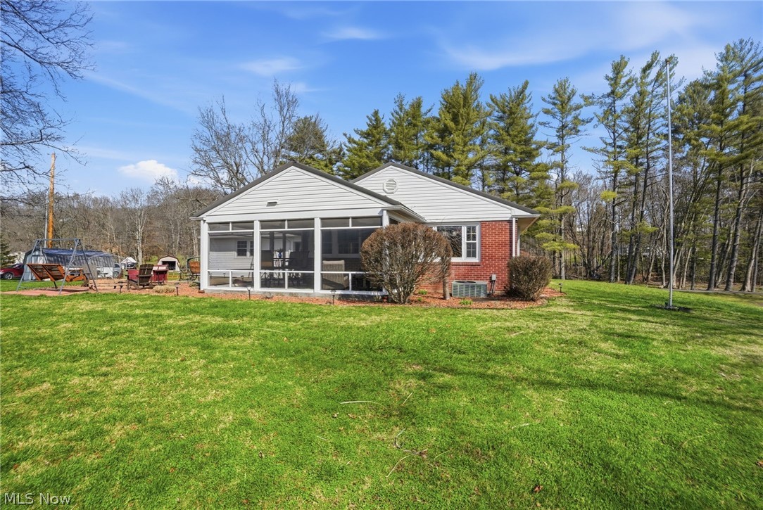 6655 Ceramic Road Crooksville, OH 43731 - Photo 27 of 34 Back of property featuring a yard, brick siding, a sunroom, and view of scattered trees