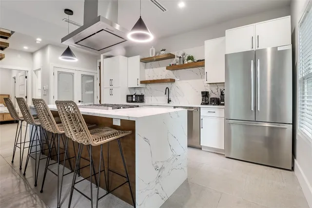 a kitchen with stainless steel appliances granite countertop a sink a stove a refrigerator and a refrigerator