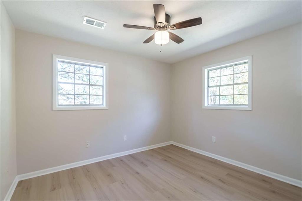 511 Lee Byrd Road Loganville, GA 30052 - Photo 17 of 32 an empty room with wooden floor ceiling fan and windows