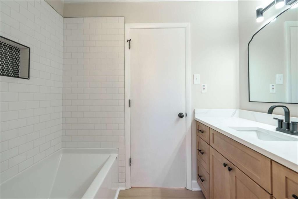 511 Lee Byrd Road Loganville, GA 30052 - Photo 23 of 32 a bathroom with a granite countertop sink a mirror and a bathtub