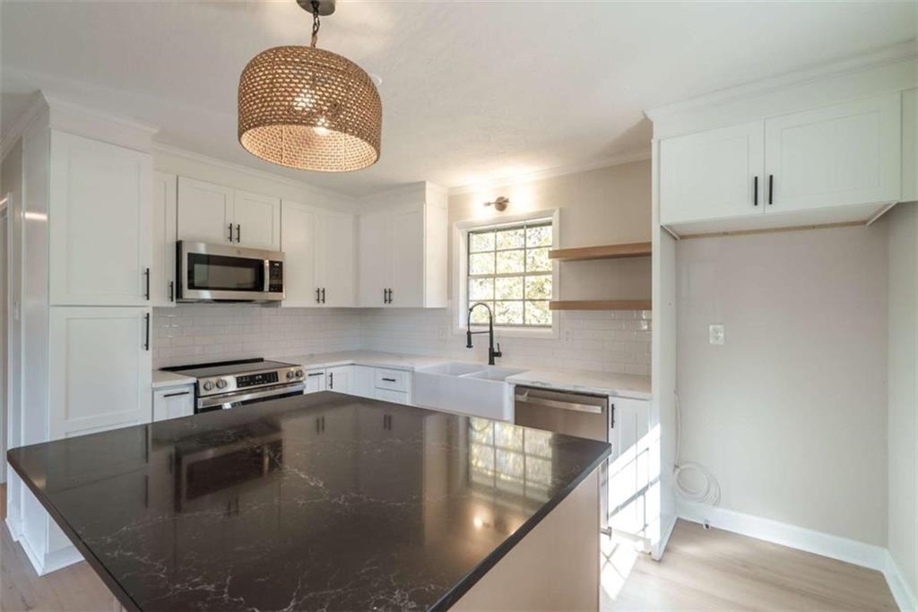511 Lee Byrd Road Loganville, GA 30052 - Photo 10 of 32 a kitchen with stainless steel appliances granite countertop a sink a stove and a microwave