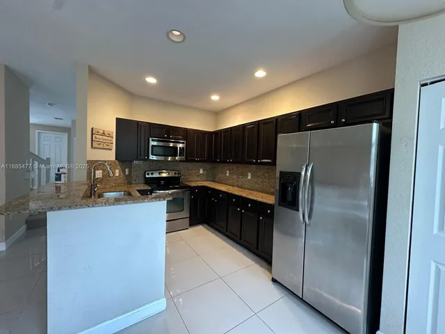 a kitchen with stainless steel appliances granite countertop a refrigerator a stove a sink a microwave and a refrigerator