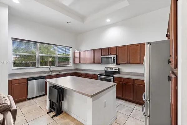 a kitchen with stainless steel appliances granite countertop a stove top oven a sink dishwasher and a refrigerator