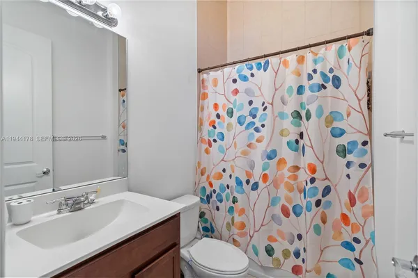 a bathroom with a sink toilet and shower curtain